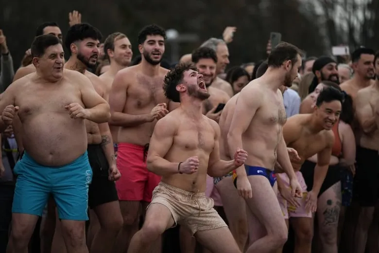People react as they're about to take a dip in ocean water on New Year's Day.