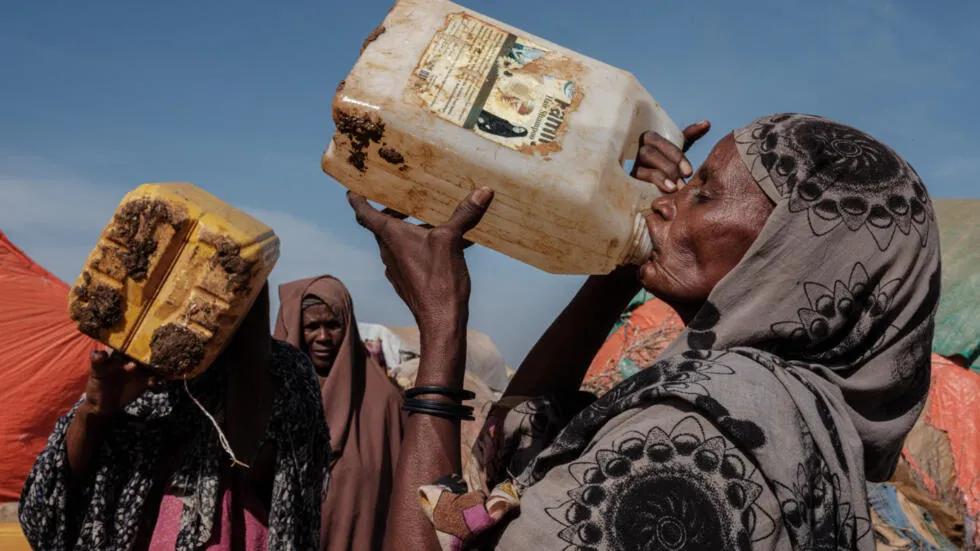 Une déplacée boit de l'eau dans une distribution d'eau dans le campement de Muuri, à Baidoa, en Somalie, le 13 février 2022.