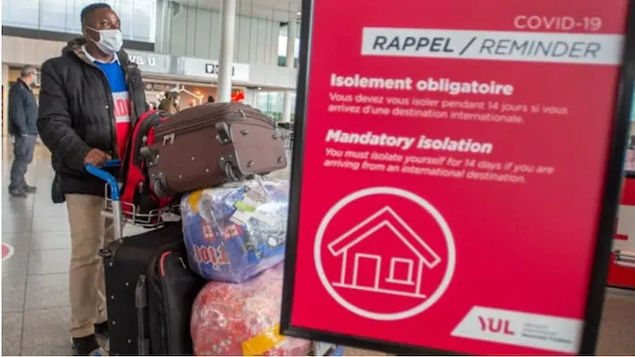 一个游客带着口罩，推着行李在多伦多机场排队。